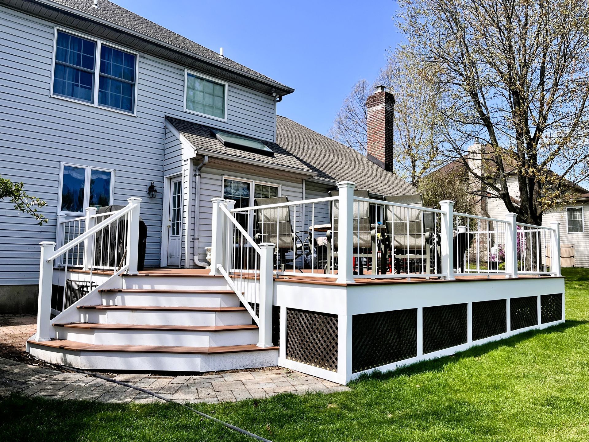Backyard deck with white railings, steps, and a house exterior on a sunny day