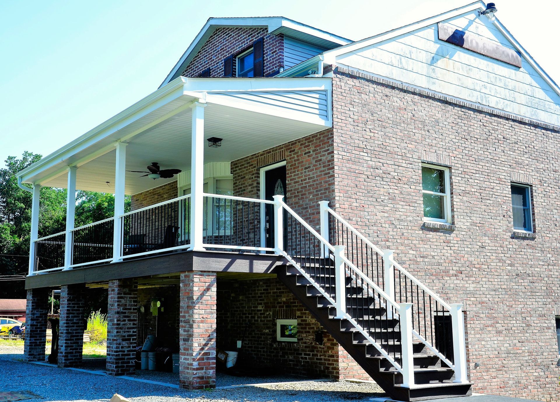 Brick house with a covered porch and exterior staircase on a sunny day