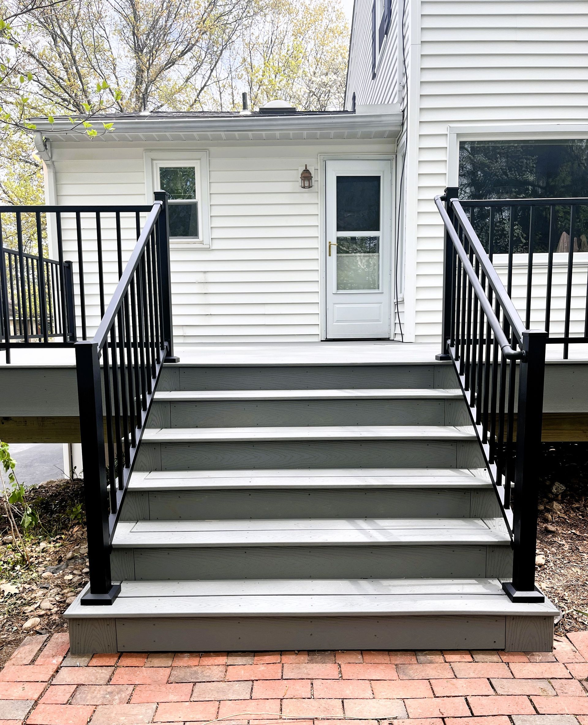Front steps with black railings leading to a white house entry door and small landing.