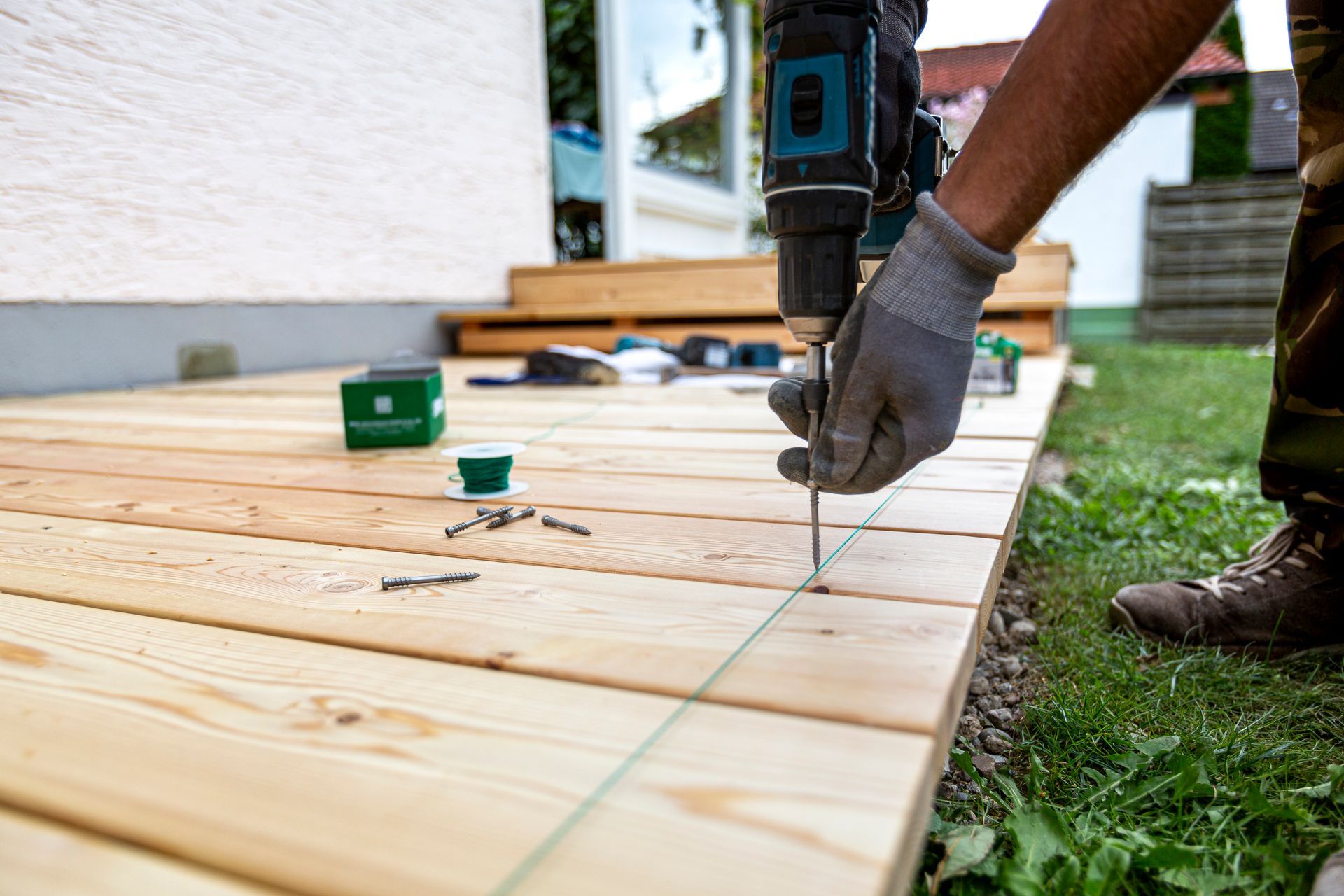 A man is using a drill to drill a hole in a wooden deck.
