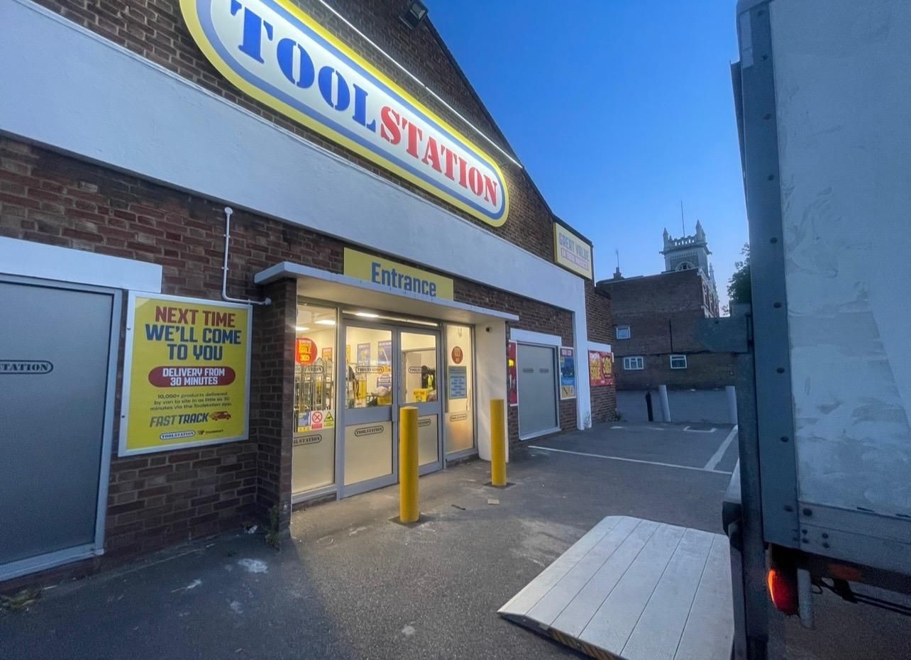 Toolstation storefront with yellow entrance doors and signs, viewed from a parking lot