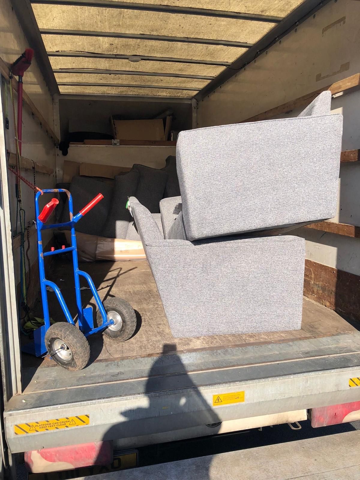 Truck bed loaded with large gray foam blocks and a blue hand truck inside an open trailer