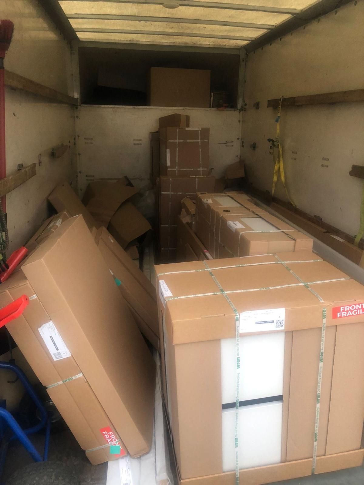 Packed cardboard boxes stacked inside a truck trailer or loading van.