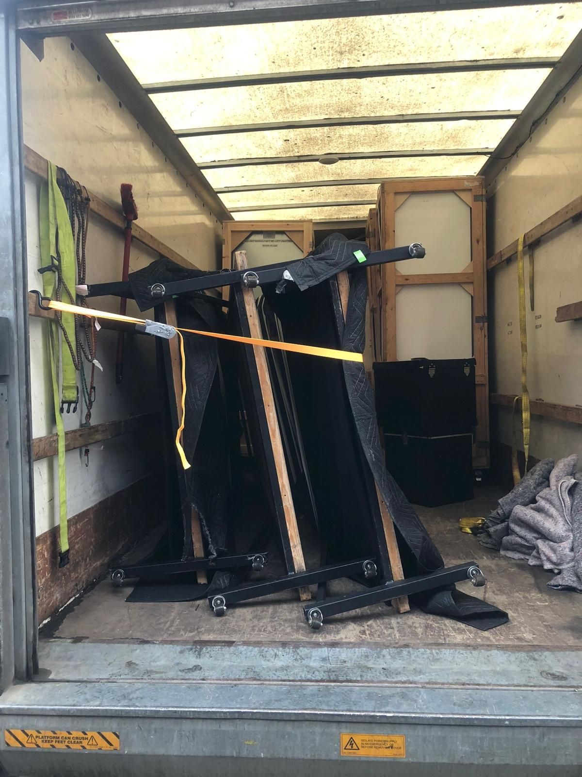 Truck trailer loaded with a tipped black exercise machine strapped to the floor