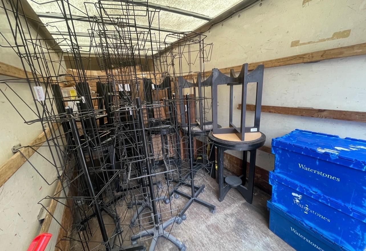 Storage room with stacked metal frames and blue bins under a covered roof