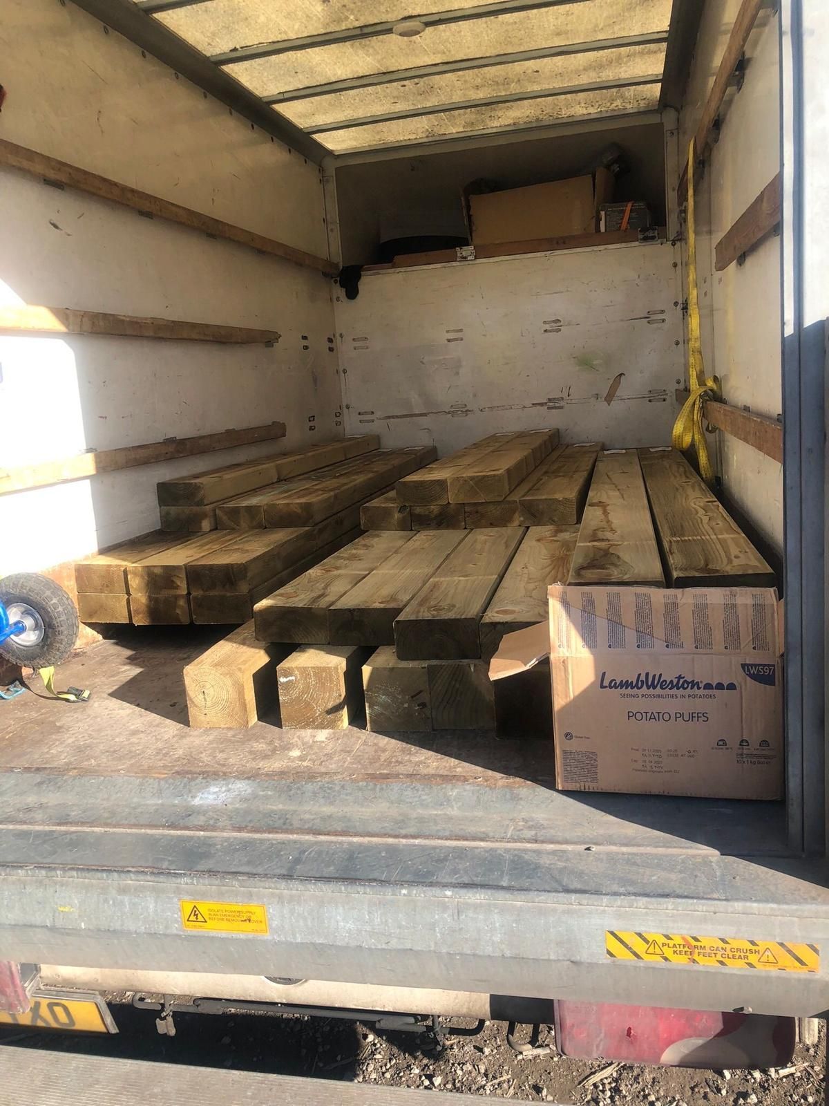 Truck trailer interior loaded with stacked wooden beams and cardboard boxes