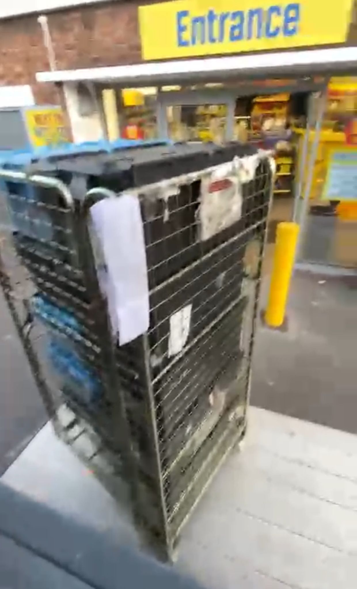 Stacked shopping carts outside a store entrance under a yellow “Entrance” sign