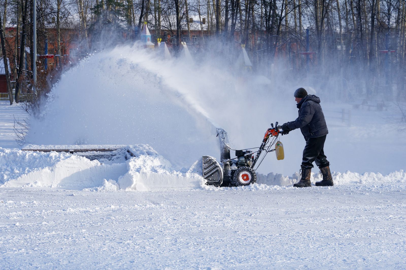 Man using a snowblower, clearing snow from a snowy area.
