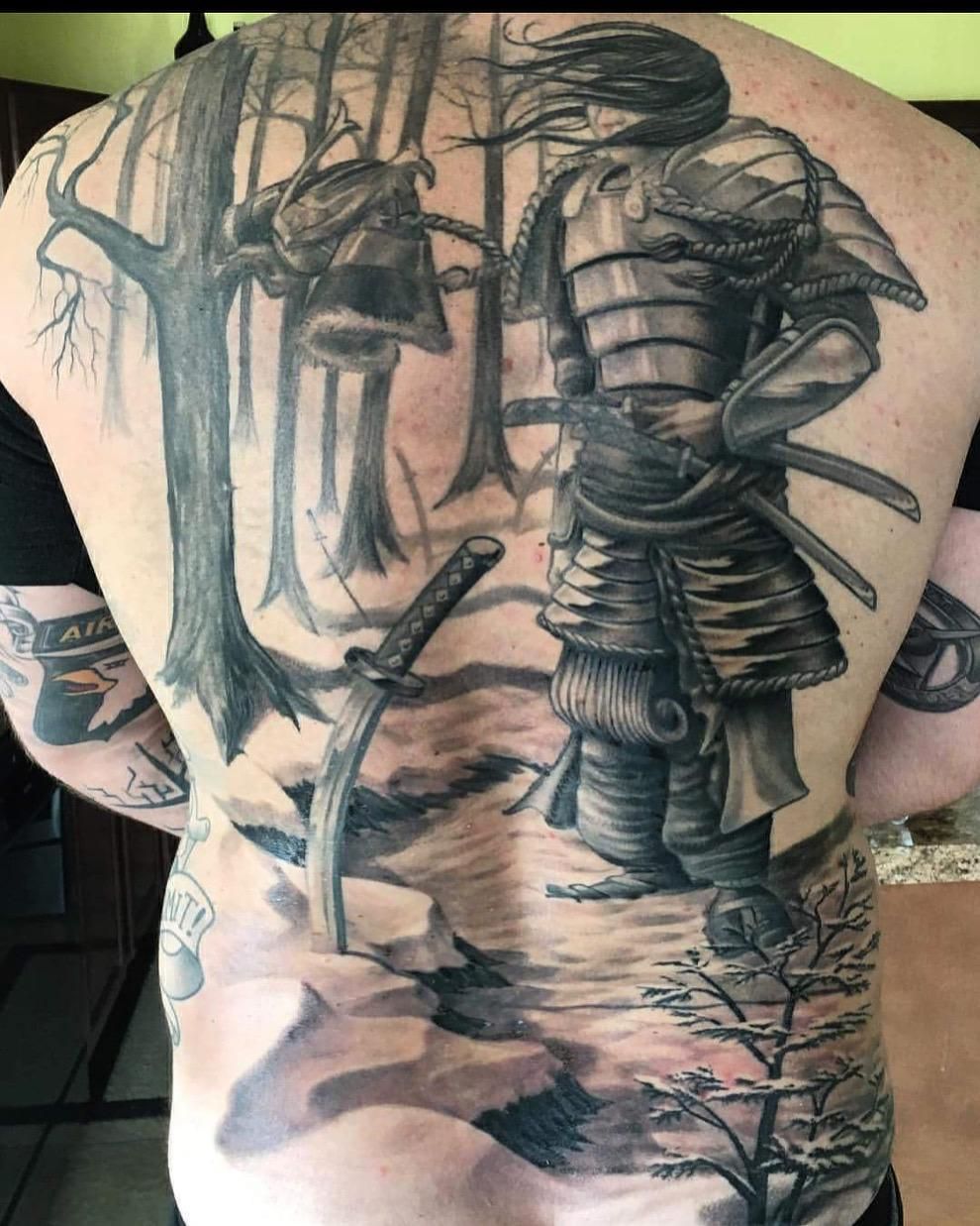 A man has a tattoo of a samurai on his back