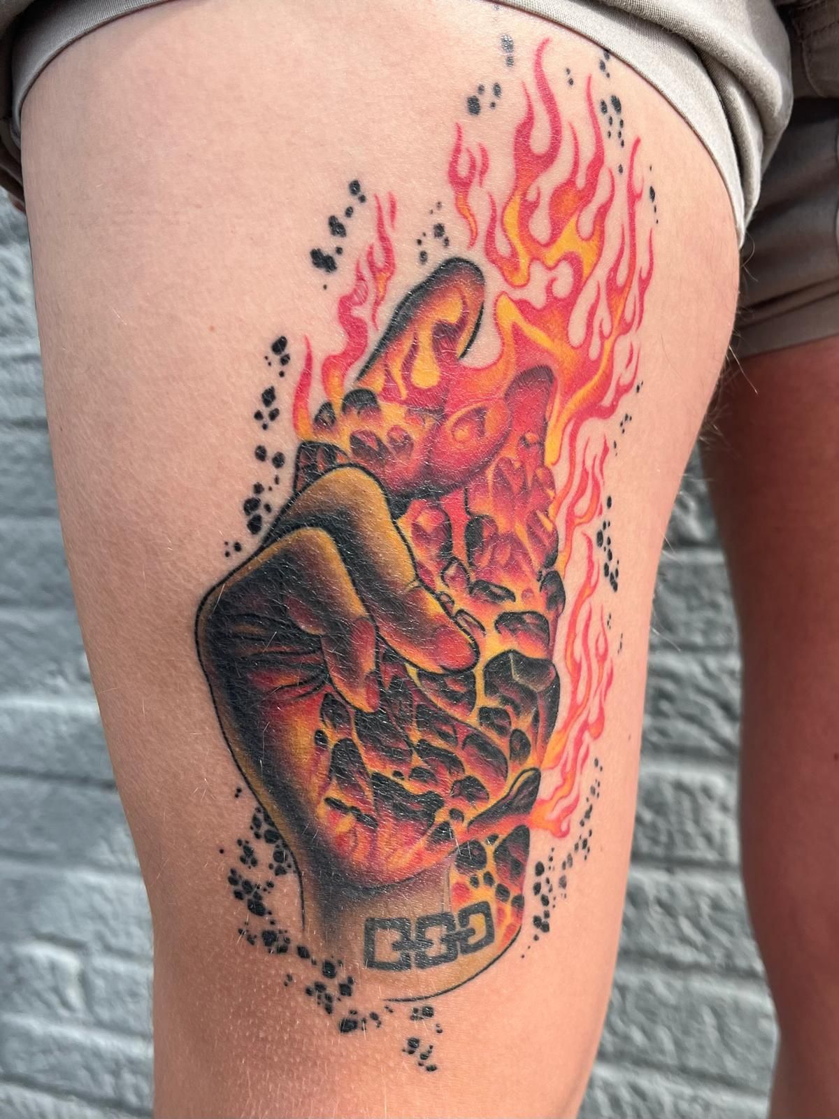 A tattoo of a fist with flames and the number 666 on it