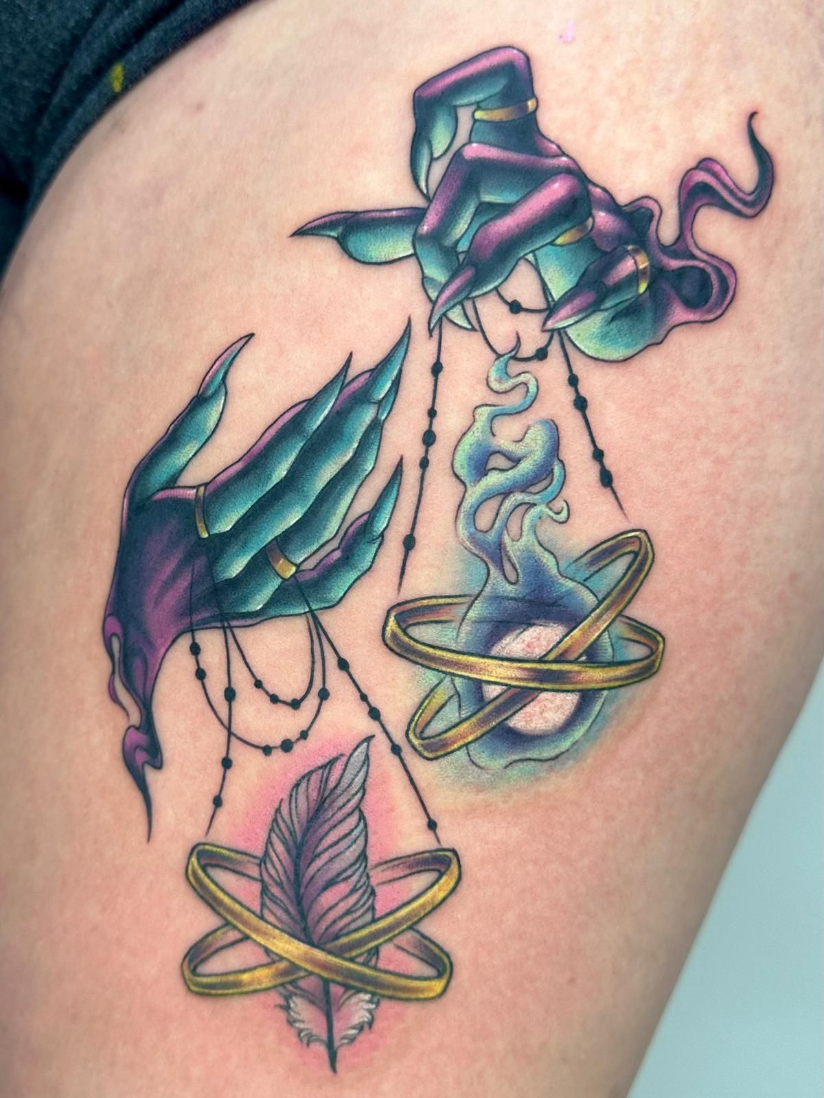 A tattoo of a witch 's hands with scales and feathers