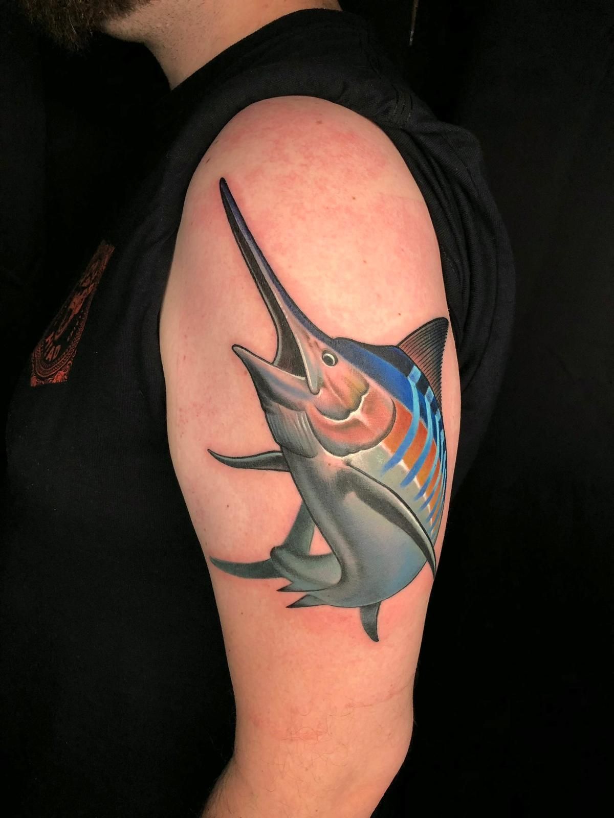 A man has a tattoo of a marlin on his arm.