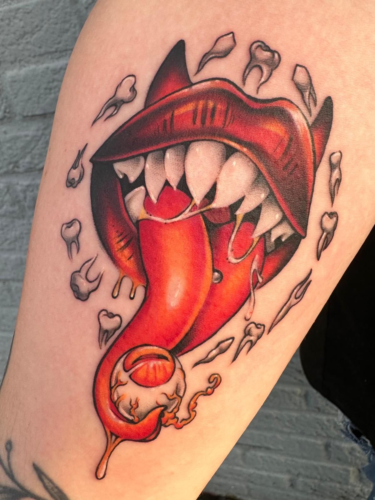 A tattoo of a devil 's mouth with a red pepper sticking out of it