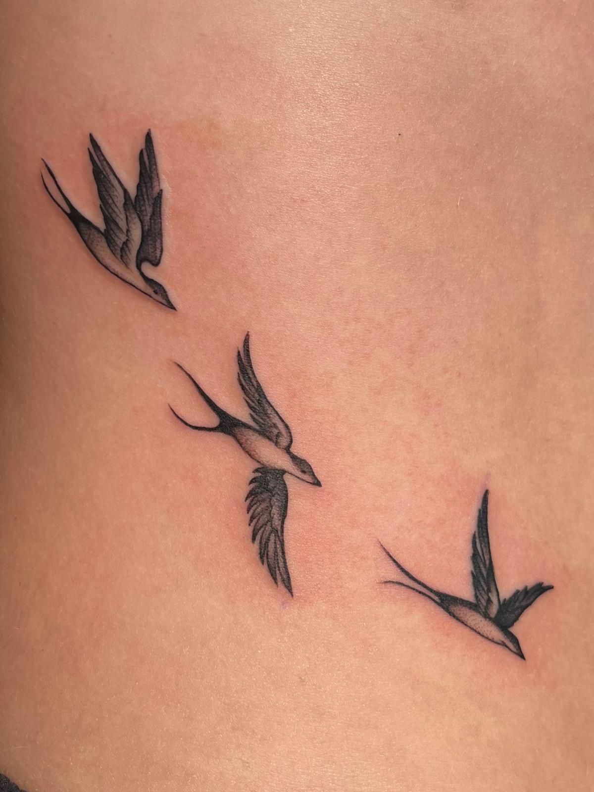 Three birds are flying in a row on a person 's stomach.