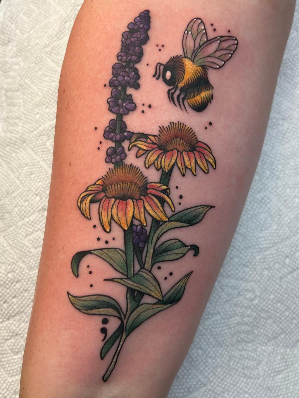 A tattoo of a bee and flowers on a person 's arm