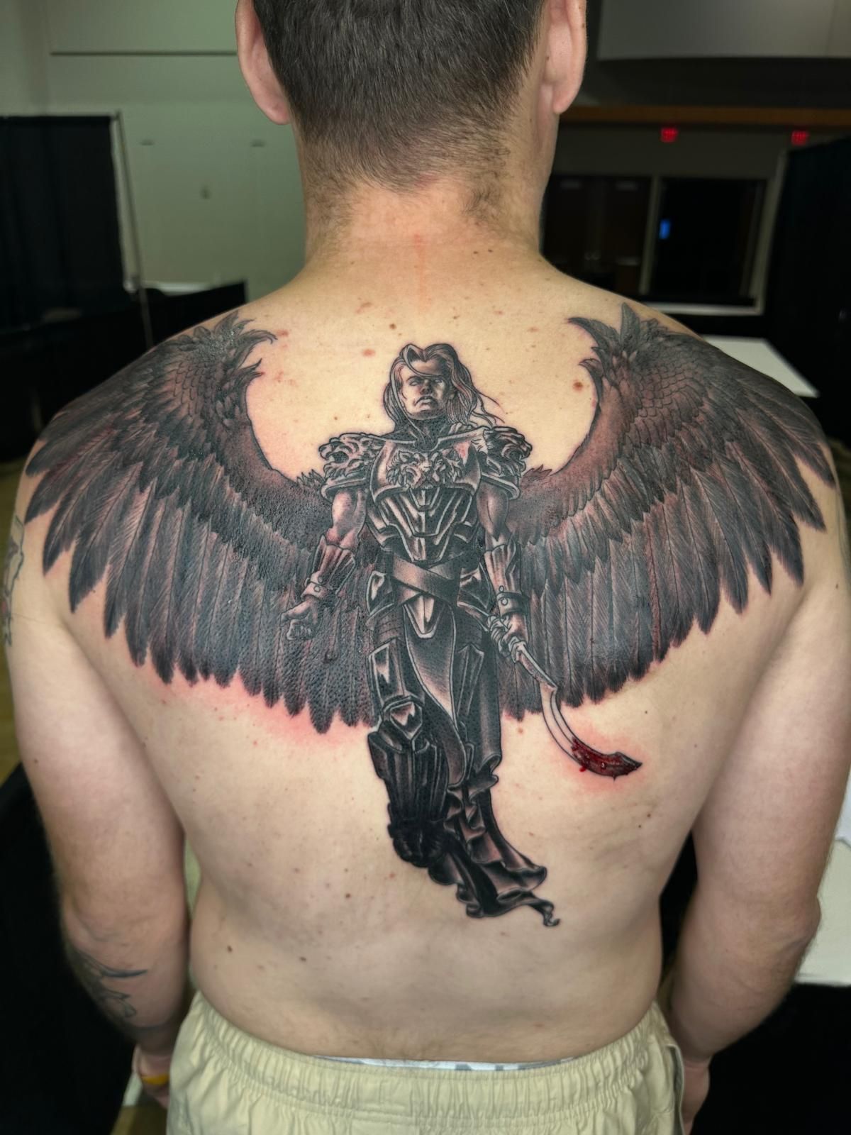 A man has a tattoo of an angel on his back.