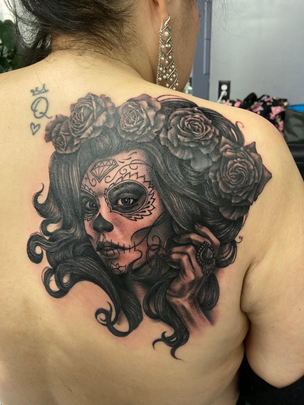A woman has a sugar skull tattoo on her back