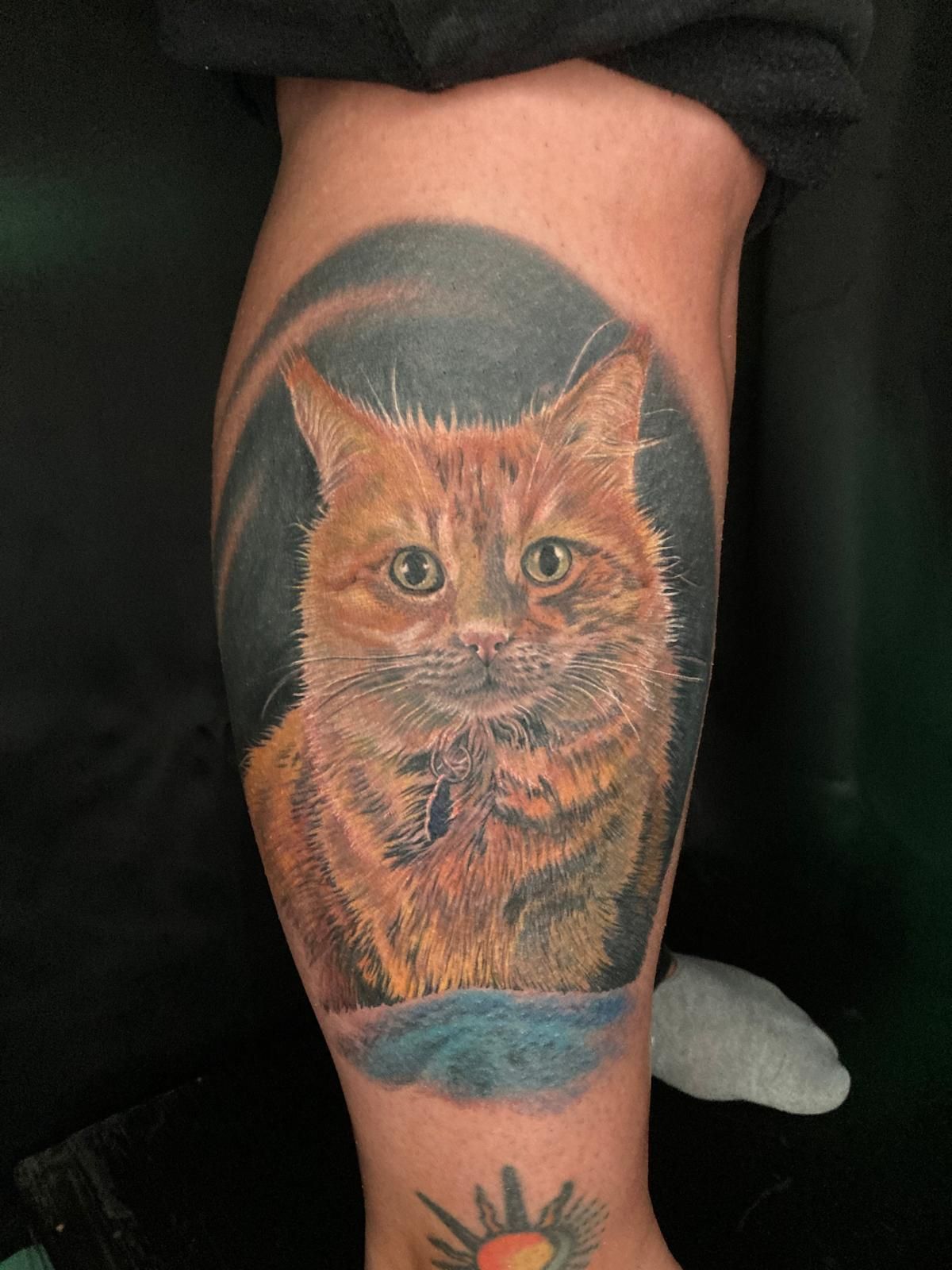 A person has a tattoo of a cat on their leg