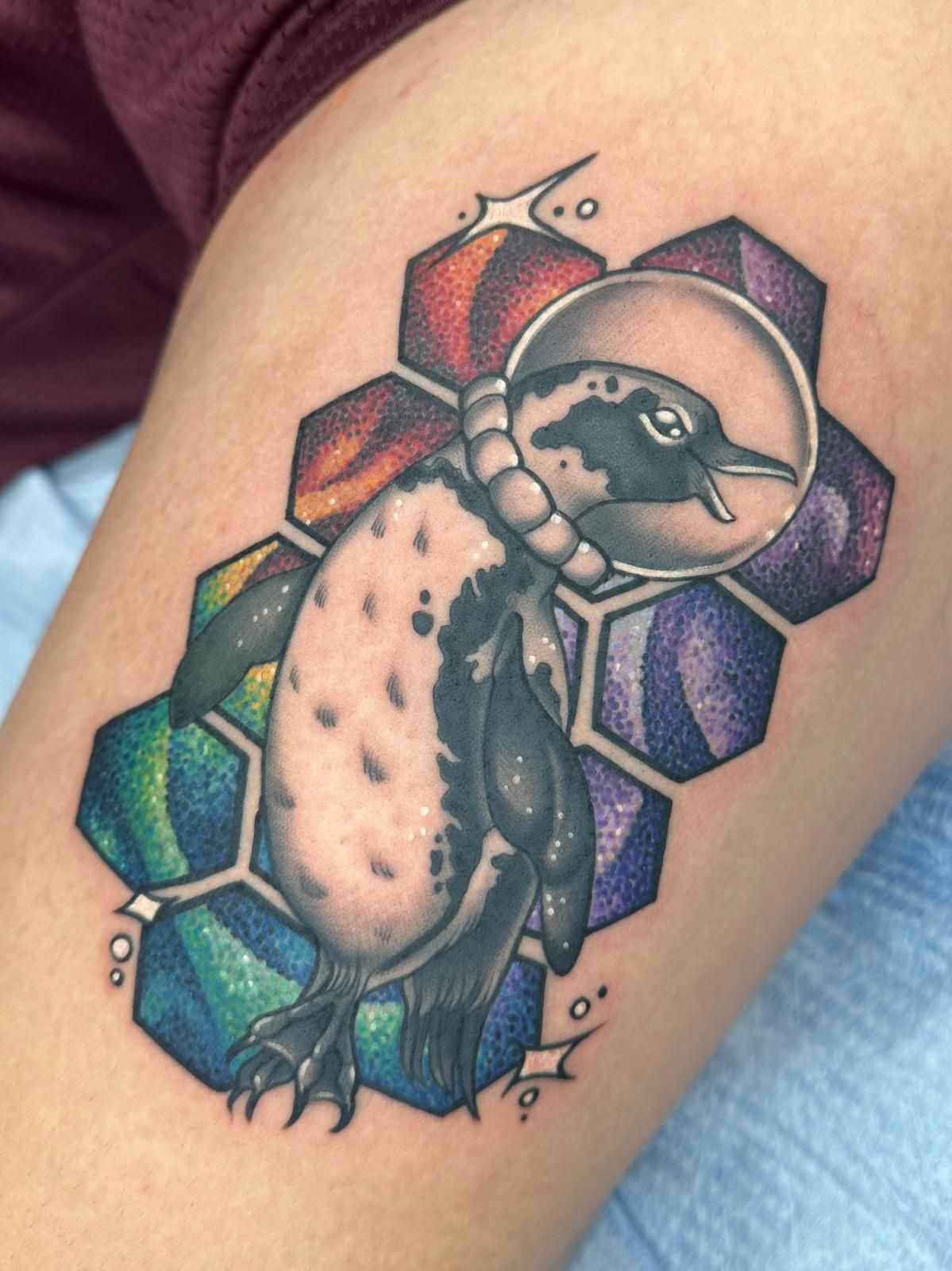 A tattoo of a penguin wearing a space helmet