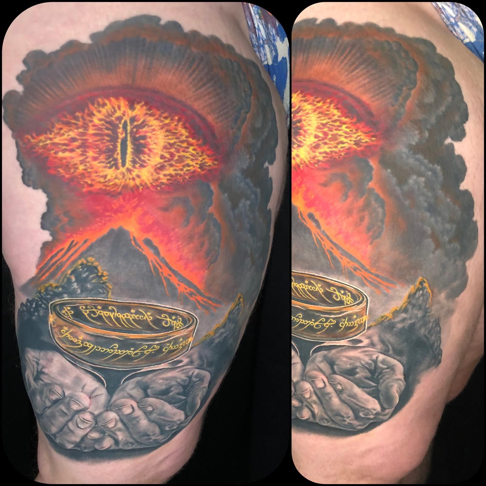 A tattoo of a person holding a ring with a volcano in the background