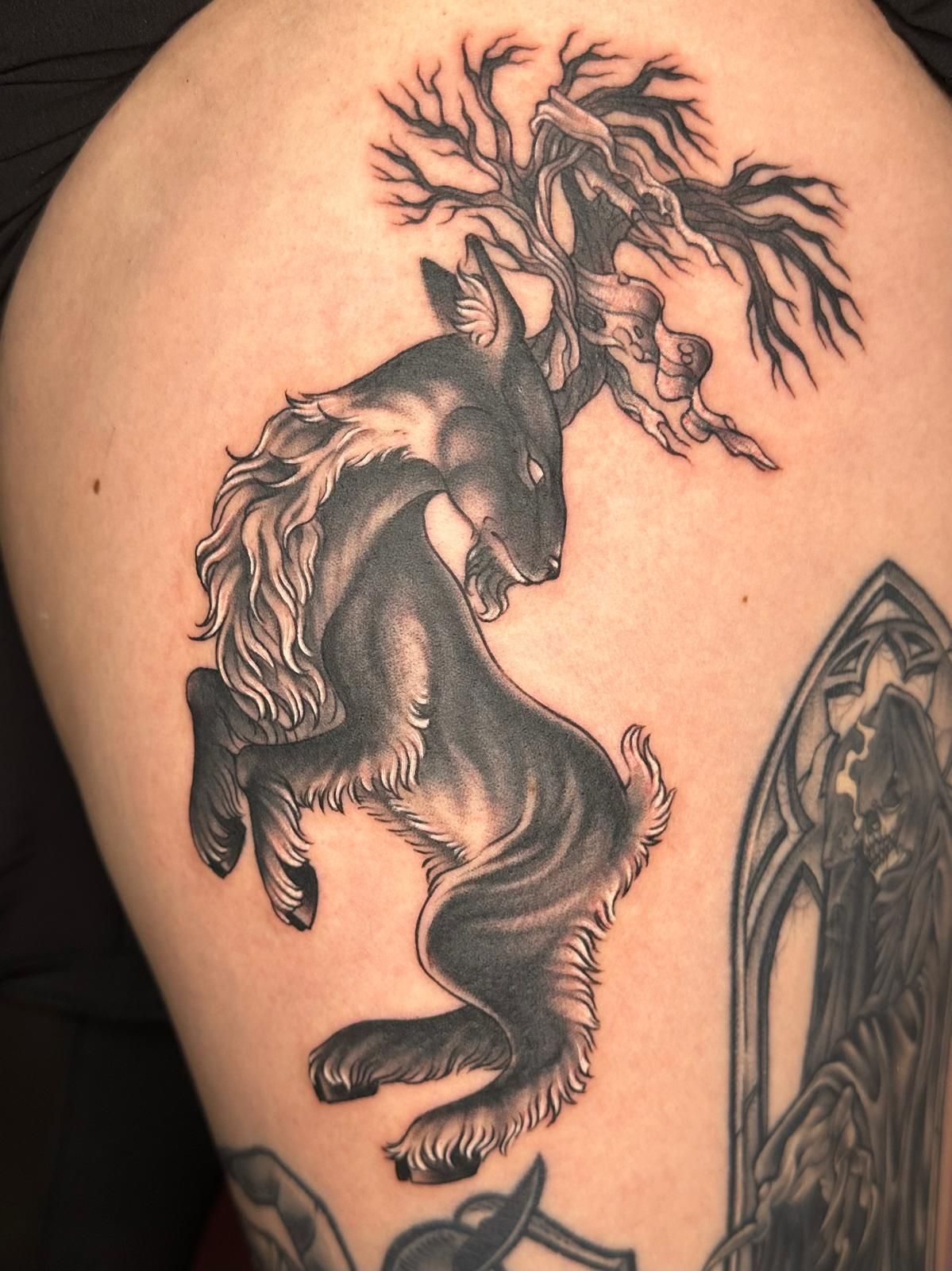 A black and white tattoo of a deer with antlers