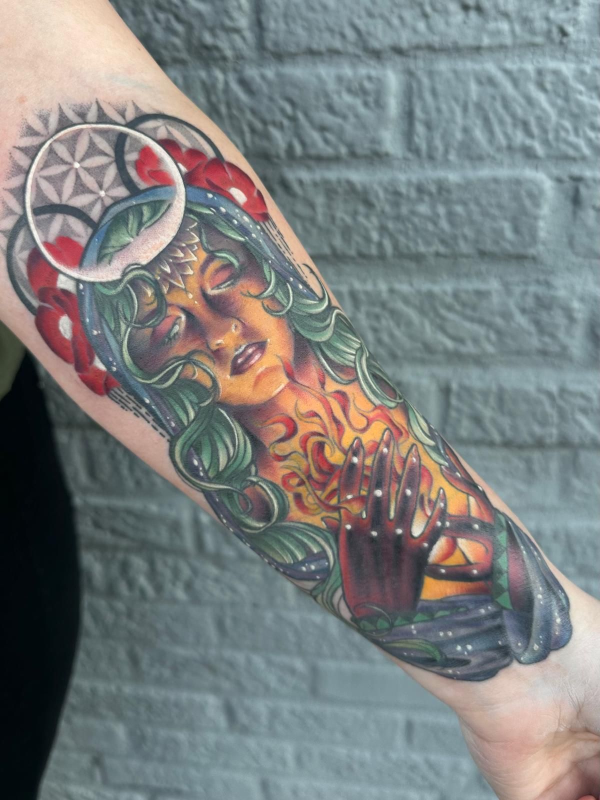 A woman has a tattoo of a woman 's face on her forearm.