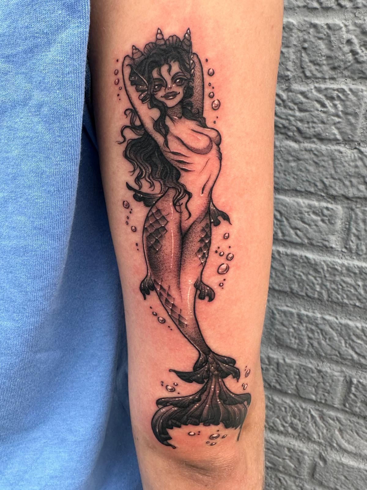 A person has a tattoo of a mermaid on their arm