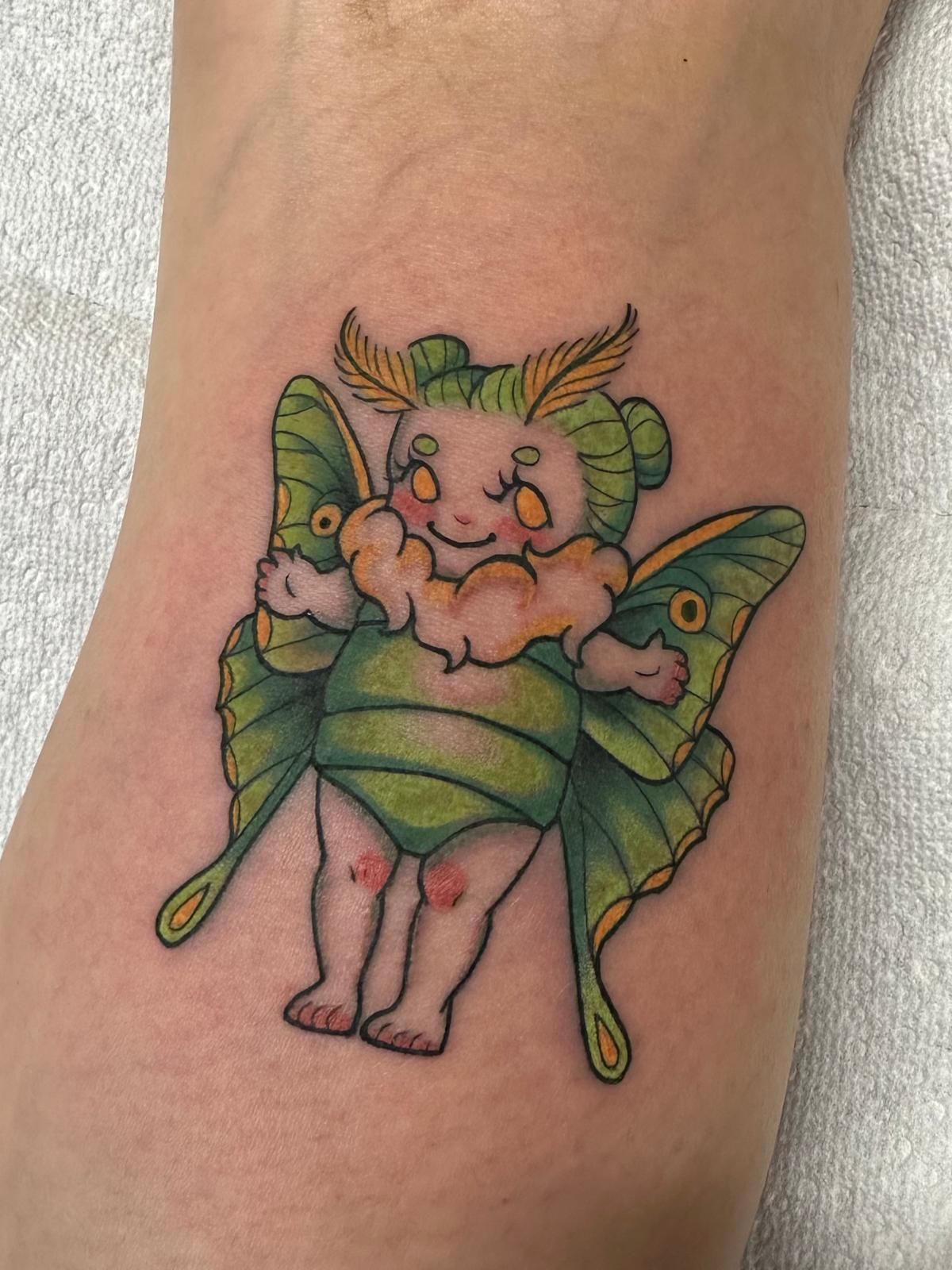 A tattoo of a baby moth on a person's leg.