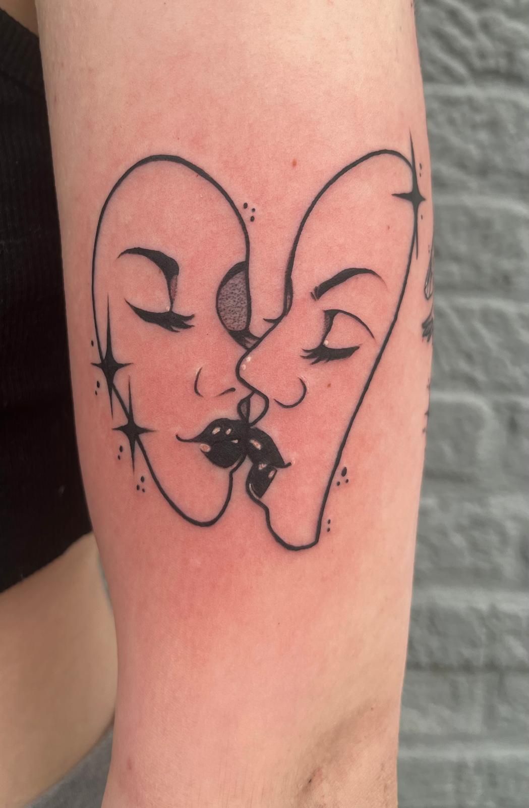 A tattoo of two faces kissing on a person's arm