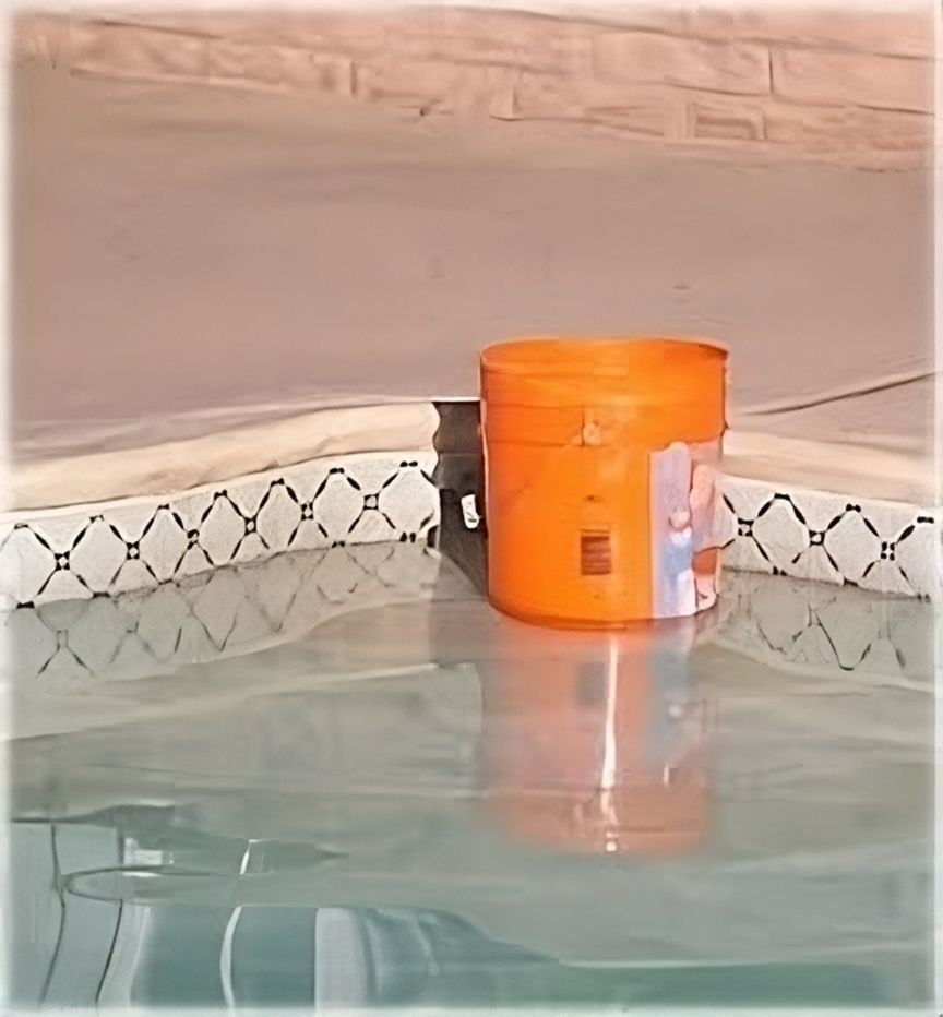 An orange bucket sits on the edge of a pool