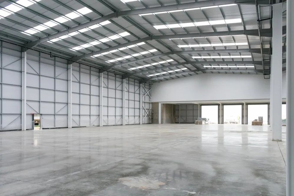 A Large Empty Warehouse With a Concrete Floor — Russell Taber Electrical & Solar in Lake Albert, NSW