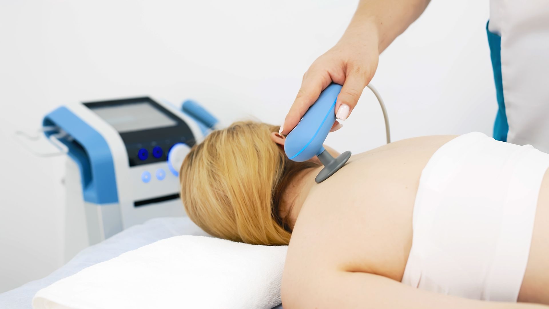 Therapist using a handheld device on a patient’s back during a treatment session