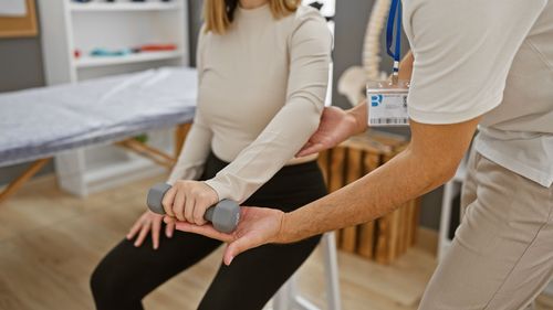 Physical therapist helping a patient stretch her wrist with a brace in a clinic