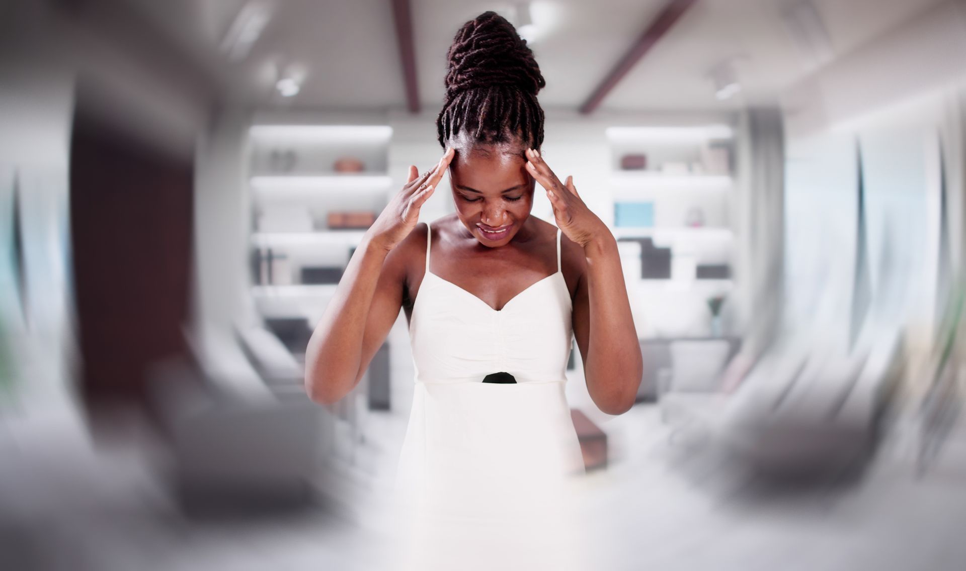Woman in a white dress adjusting her hair in a bright, modern room