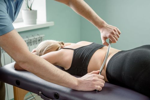 Measuring a woman's waist with a tape measure on a treatment table