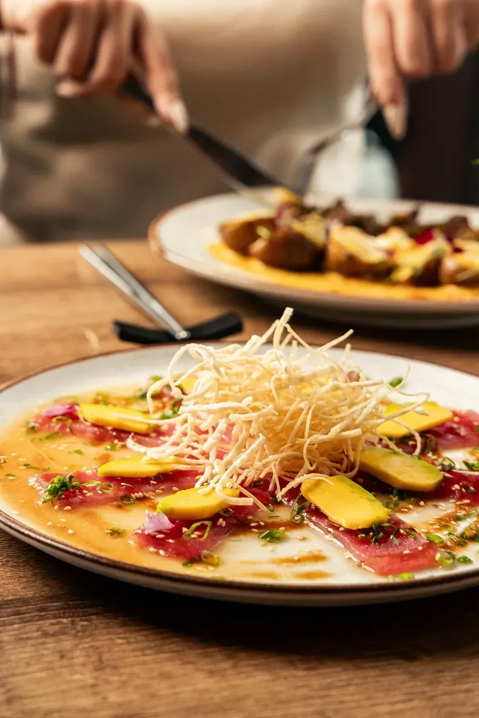 Nikkei tiradito with sliced fish, avocado, red onion and crispy potato strips.