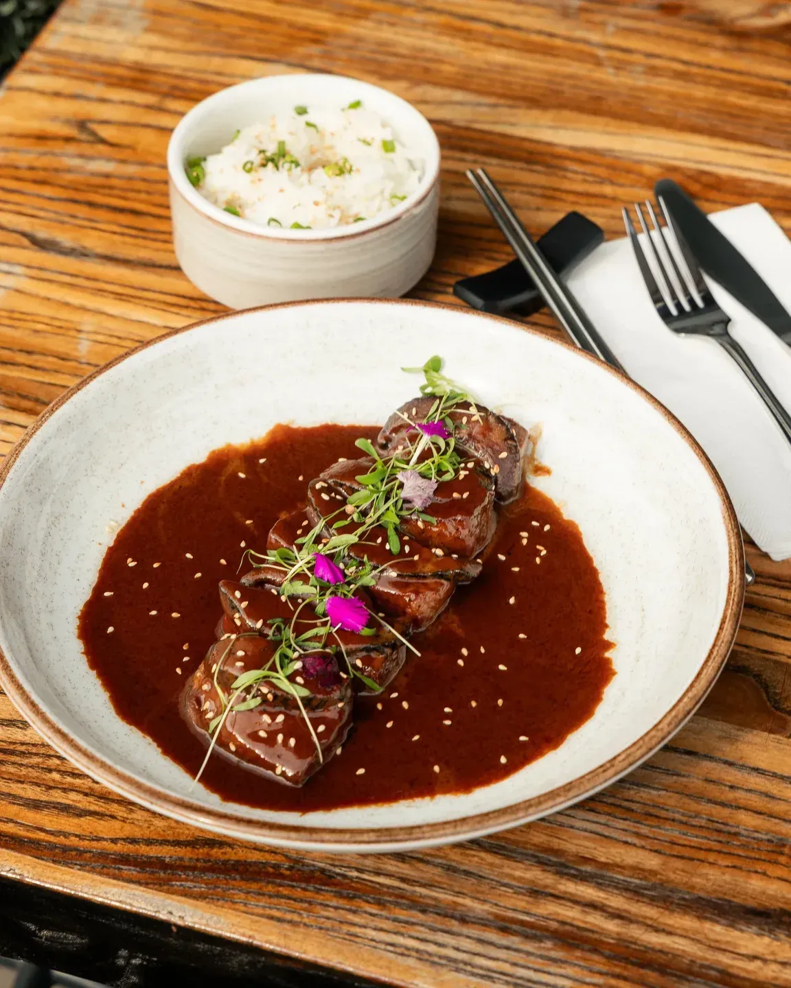 Enkai beef entrée with dark sauce, microgreens and edible flowers.