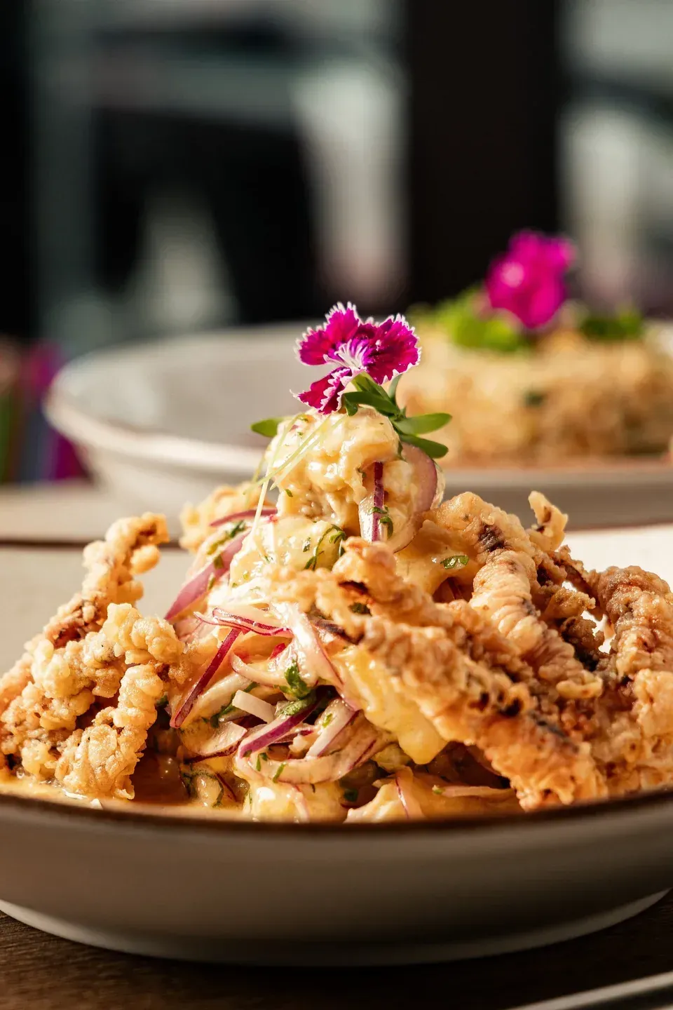 Crispy seafood dish with red onion, edible flowers and creamy sauce at Enkai.