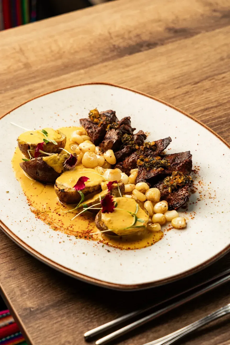 Grilled meat with yellow potatoes, corn and creamy sauce at Enkai.