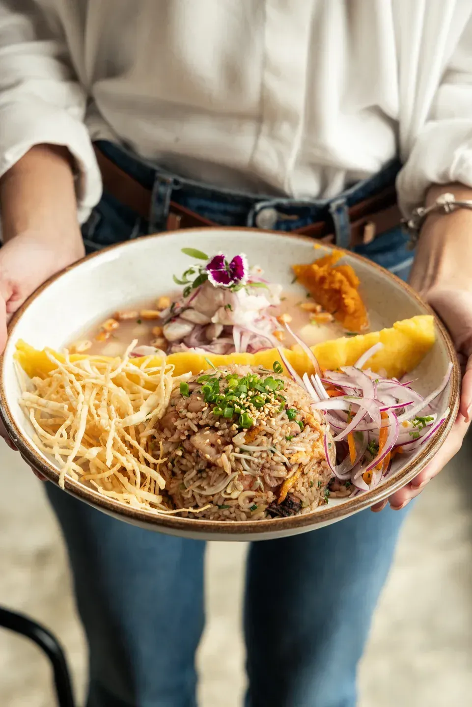 Enkai fried rice bowl with crispy potato strips, vegetables and edible flowers.