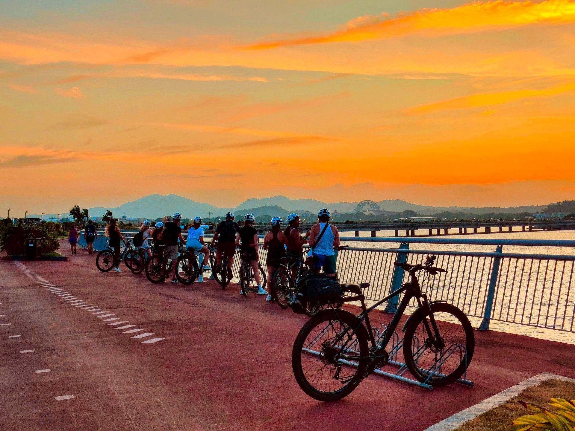 Cyclists gathered along Cinta Costera during an orange sunset on the Sunset Bike Tour in Panama City.