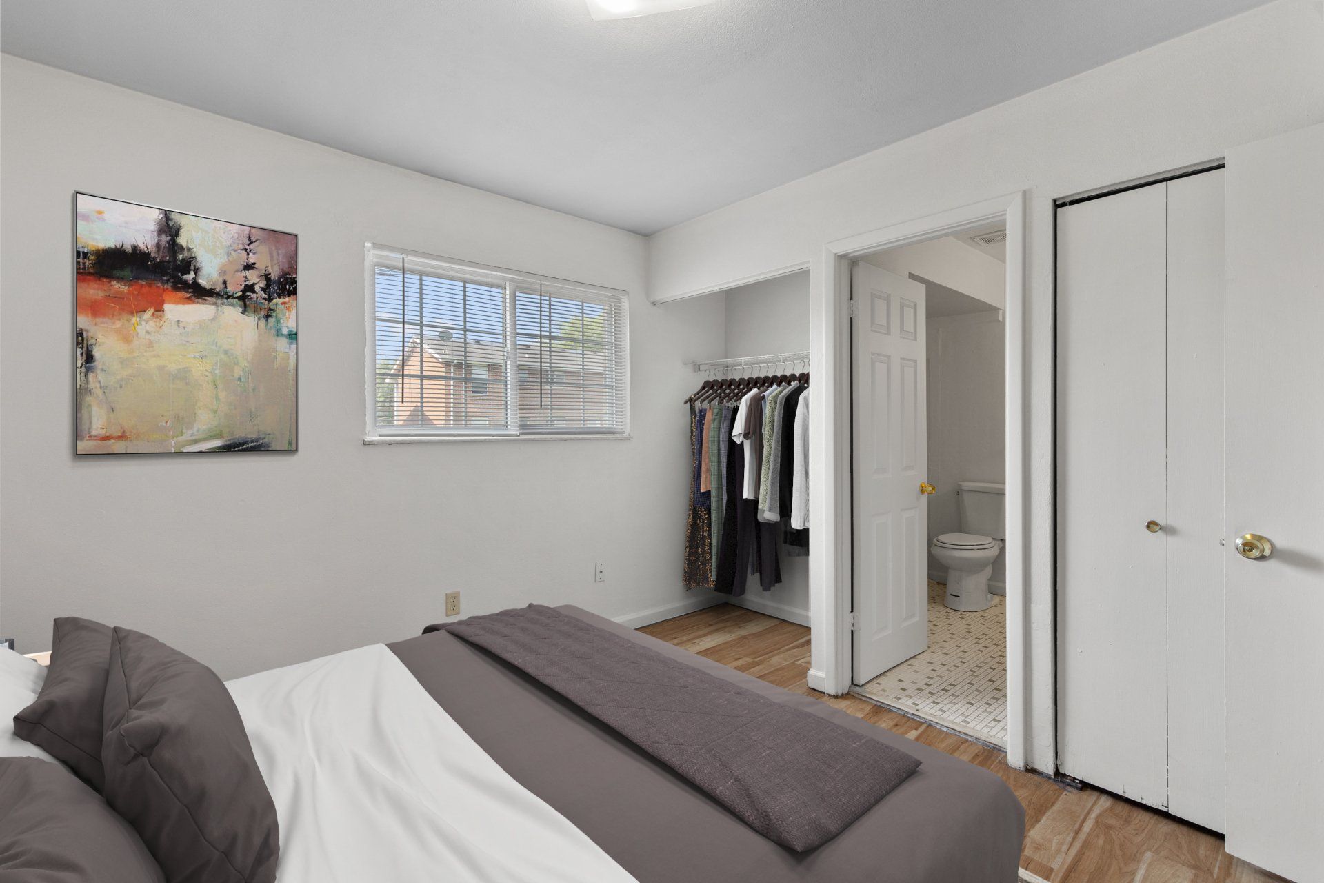 Bedroom with hardwood floors, closet, and bathroom; full-sized bed is for example only.