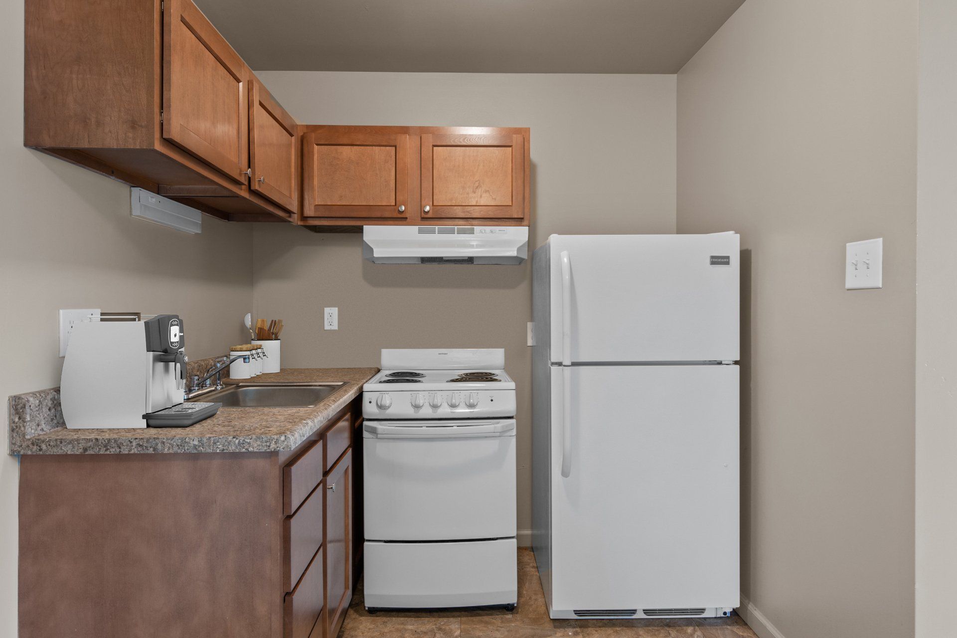 Teson Garden Apartments kitchen with light wooden cabinets, stove and refrigerator..