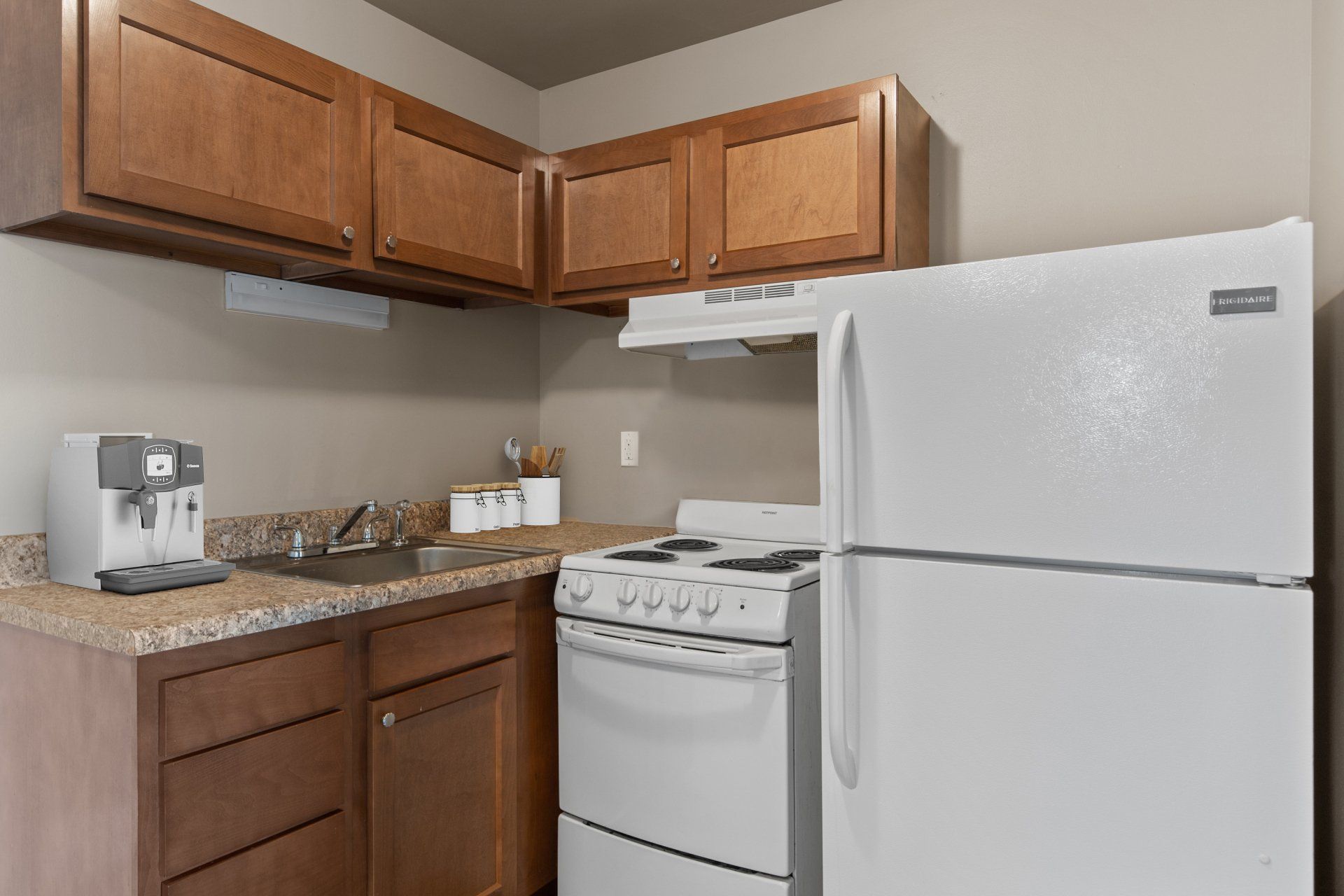 Teson Garden Apartments kitchen with light wooden cabinets, stove and refrigerator..