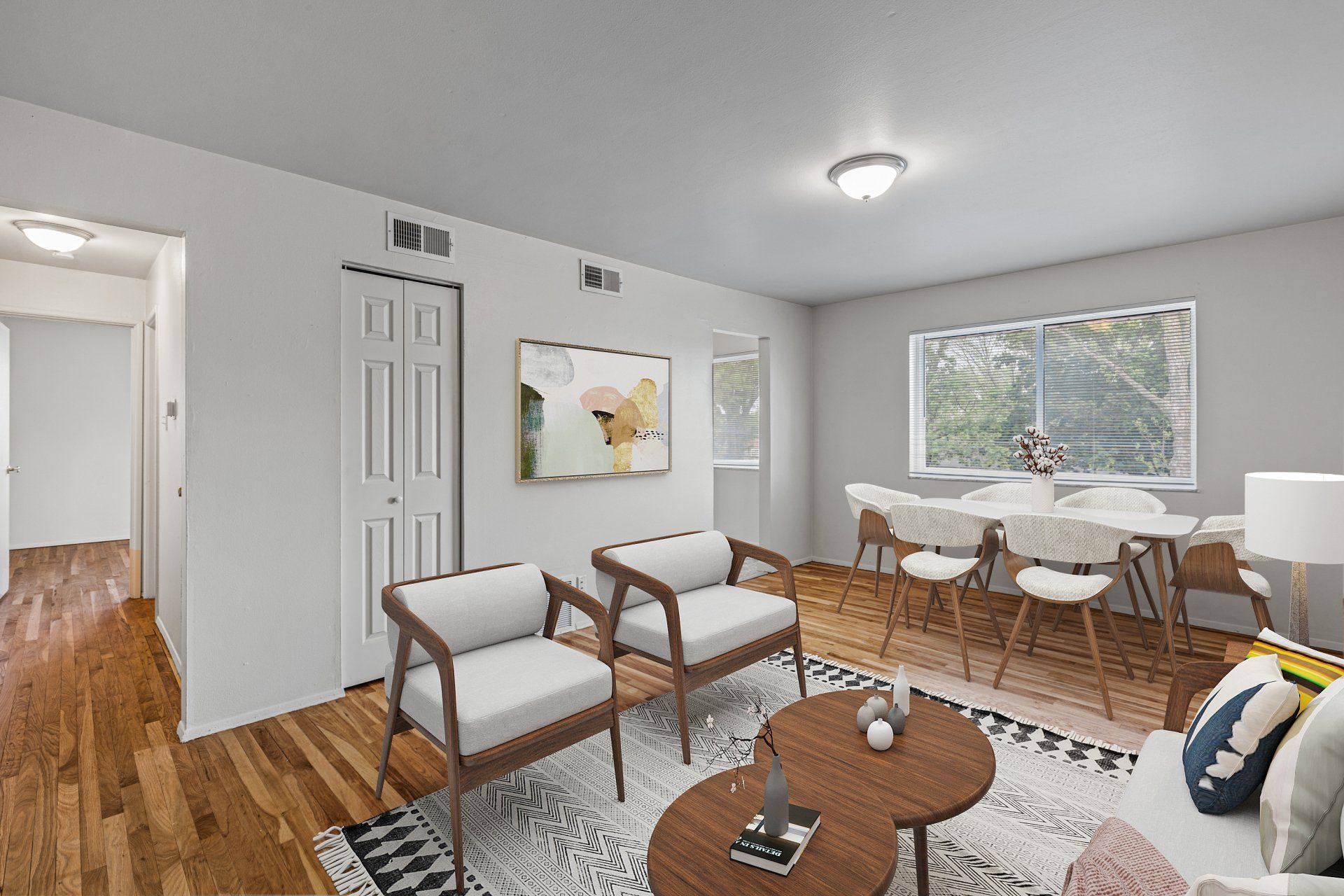 Charbonier Apartments living room with window and two chairs, coffee table, and view of dining table - furniture for examples purposes only.