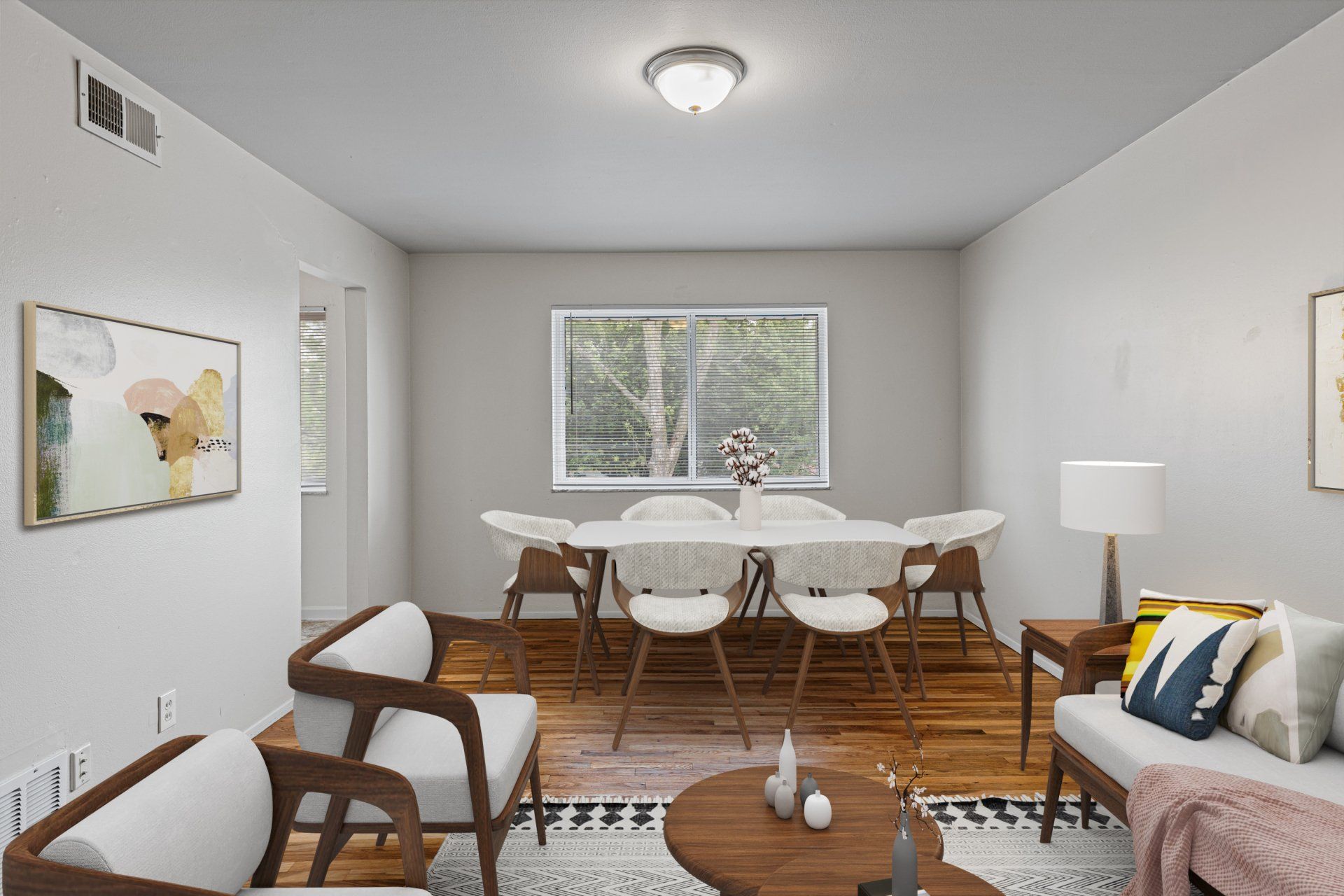 Charbonier Apartments living room with window and two chairs, coffee table, and view of dining table - furniture for examples purposes only.