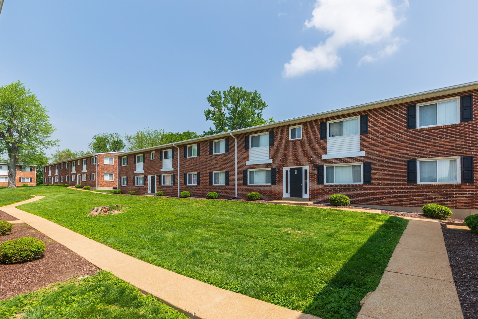 Exterior of Teson Garden Apartments brick building and large grass area in front.