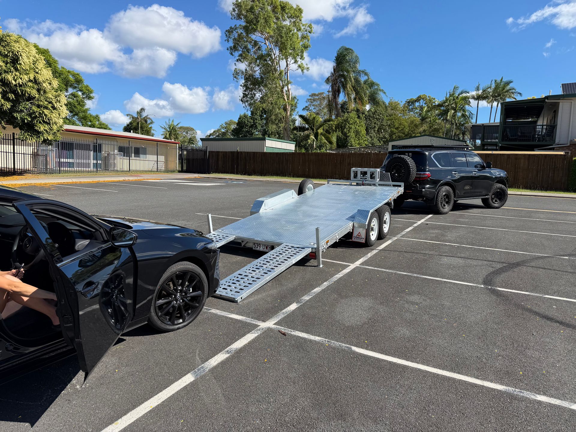TrailerMates hydraulic tilt car trailer with ramps down, hitched to a 4WD