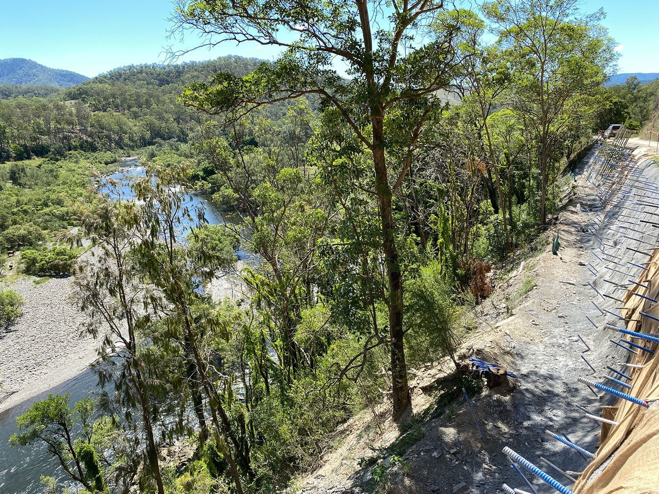 Riverside landscape with trees, a rocky bank, and a stone path beside the water
