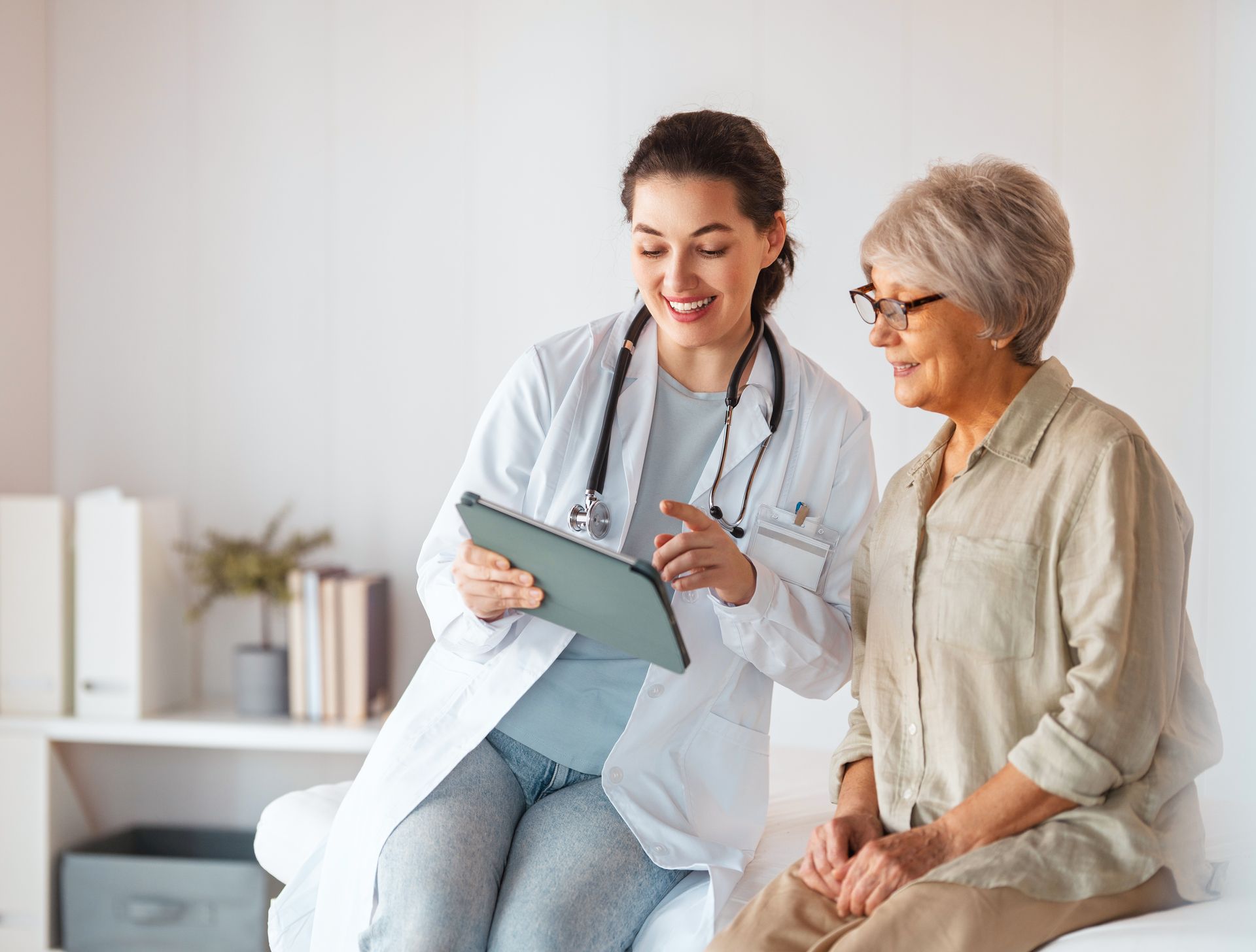 A smiling doctor in a lab coat with a stethoscope around his neck.